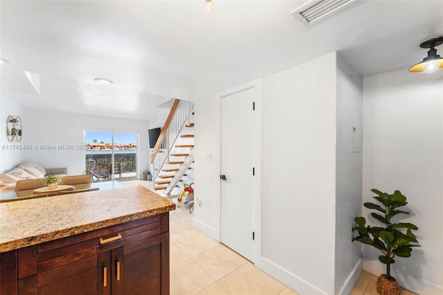 kitchen featuring light stone counters, light tile patterned floors, and dark brown cabinets