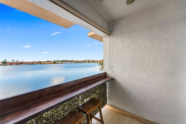 balcony with ceiling fan and a water view