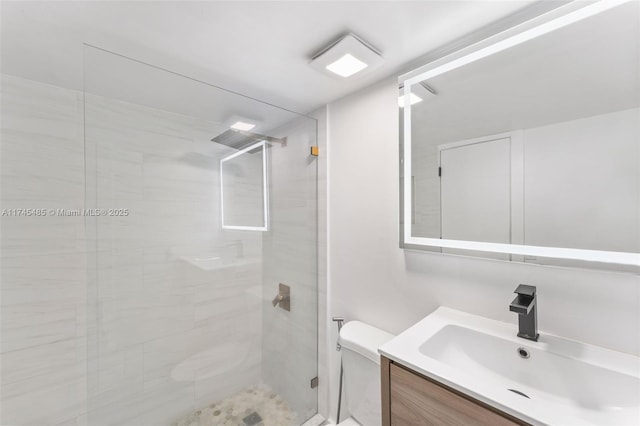 bathroom featuring vanity, a shower with door, and toilet