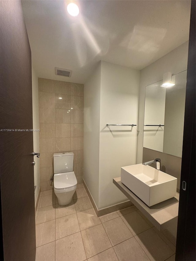 bathroom with tile patterned flooring, sink, tile walls, and toilet