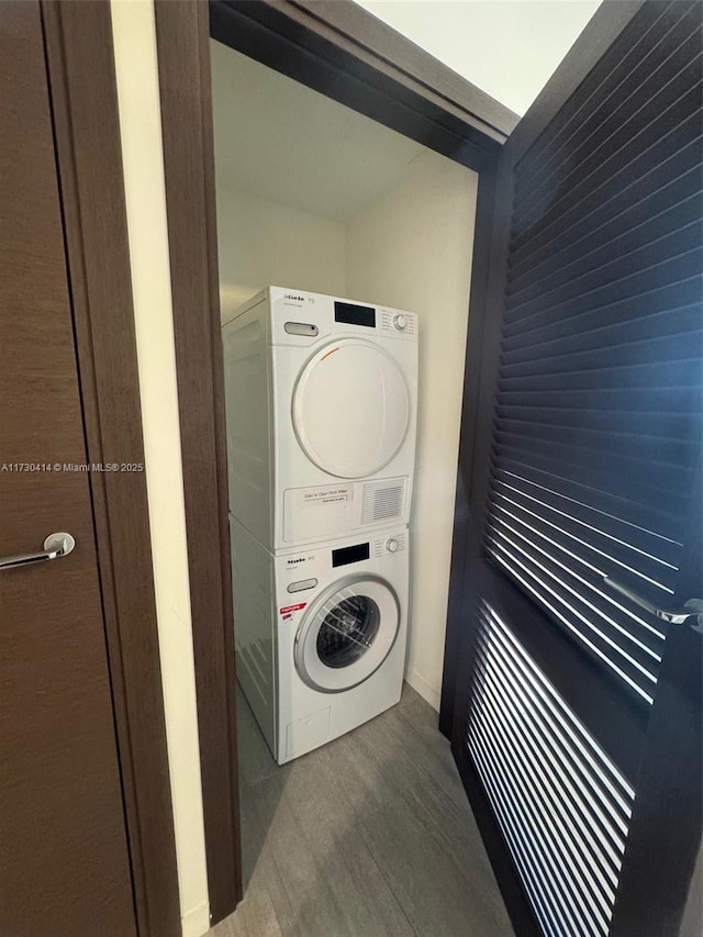 laundry area with wood-type flooring and stacked washer and clothes dryer