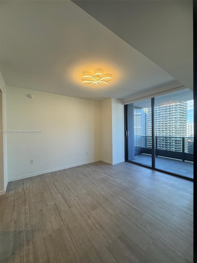 unfurnished room with light hardwood / wood-style flooring and a wall of windows