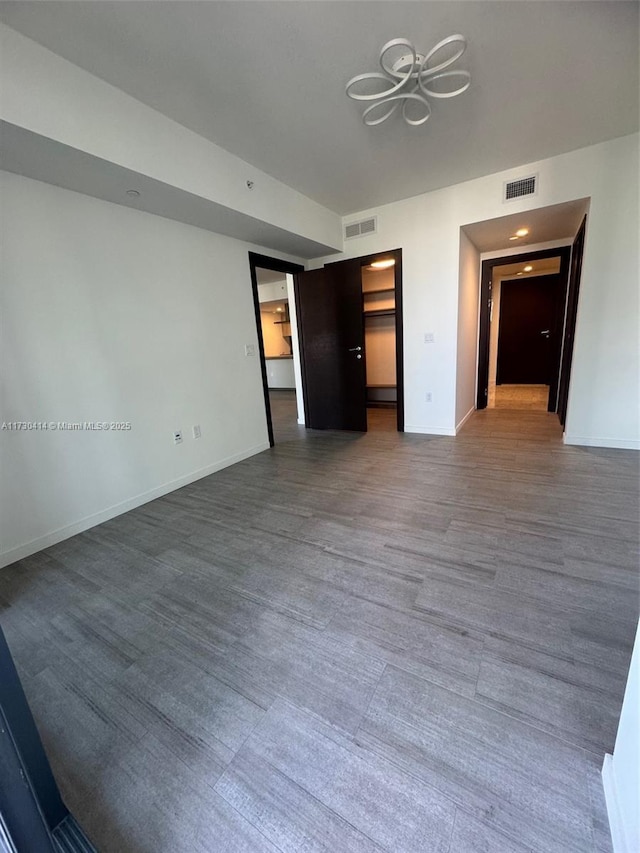 unfurnished bedroom featuring a walk in closet and wood-type flooring