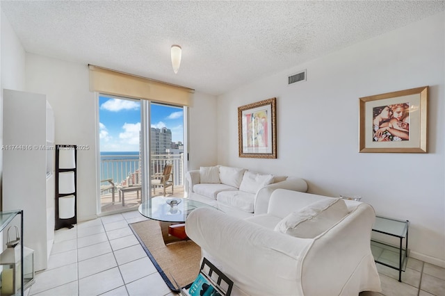 living room featuring a water view, a textured ceiling, and light tile patterned floors