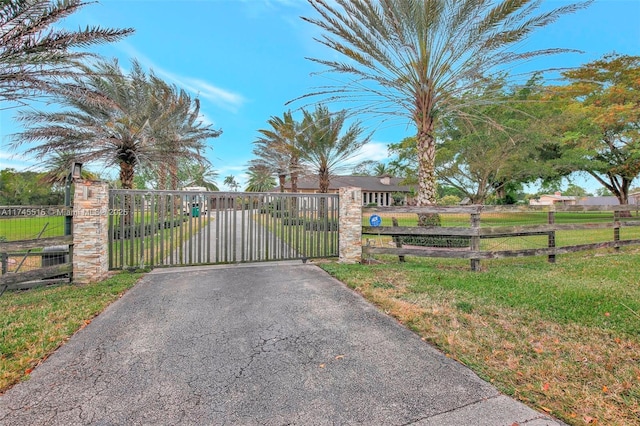 view of gate with fence and a lawn