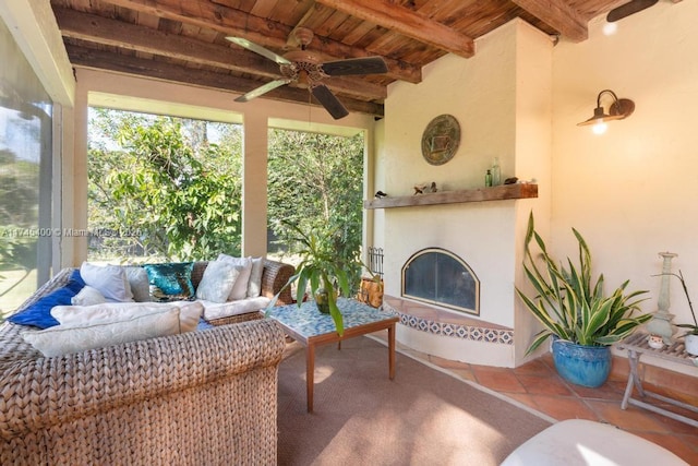 exterior space with a glass covered fireplace, beam ceiling, wood ceiling, and a ceiling fan
