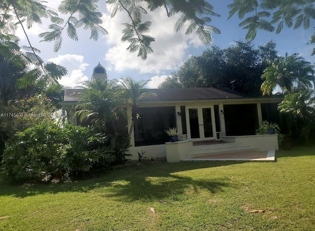 back of house with french doors and a lawn