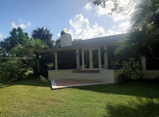 back of house with a patio area, a lawn, and french doors