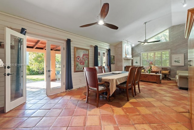 dining space with wooden walls, french doors, lofted ceiling, and ceiling fan