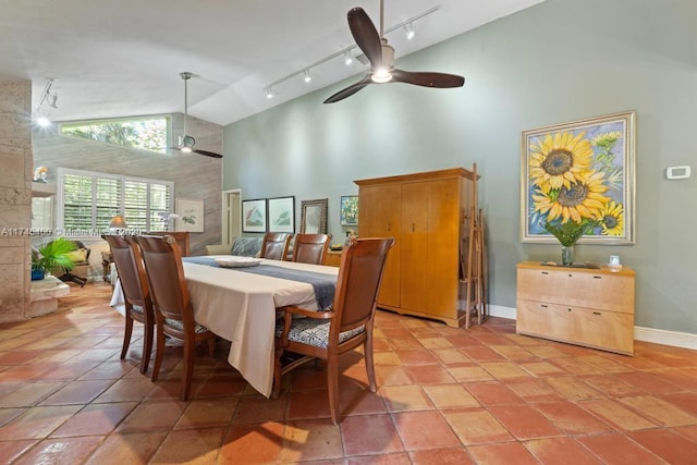 dining area featuring rail lighting, a ceiling fan, baseboards, and high vaulted ceiling