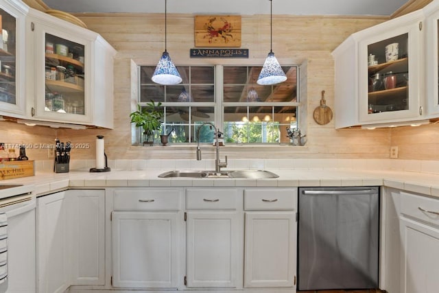 kitchen with tile counters, a sink, white cabinetry, and stainless steel dishwasher