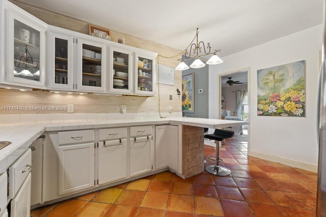 kitchen with tasteful backsplash, a peninsula, a ceiling fan, and white cabinetry