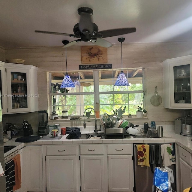 kitchen with tile counters, hanging light fixtures, backsplash, glass insert cabinets, and white cabinetry