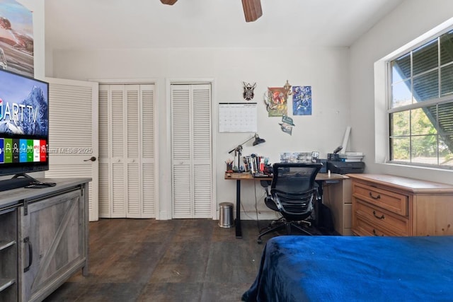 bedroom featuring dark wood-style floors, two closets, and ceiling fan