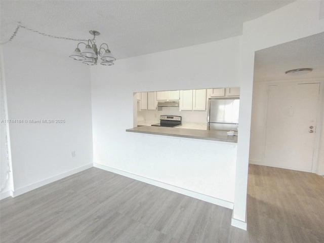 kitchen with a notable chandelier, decorative light fixtures, stainless steel appliances, and light hardwood / wood-style floors