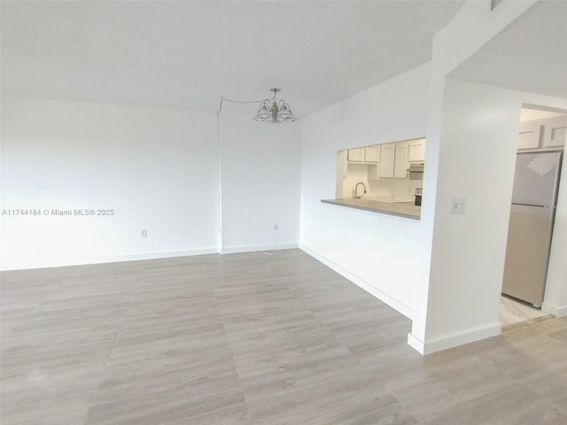 interior space featuring an inviting chandelier, lofted ceiling, and light hardwood / wood-style flooring