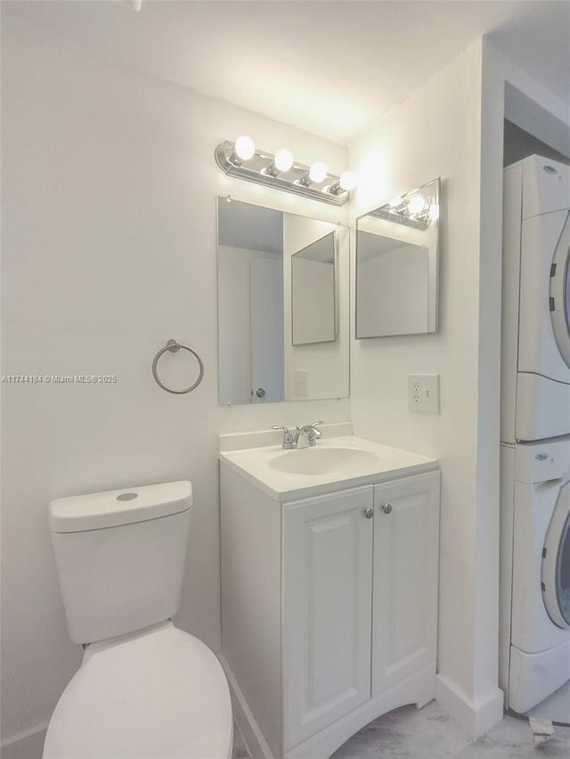 bathroom featuring vanity, stacked washer and dryer, and toilet