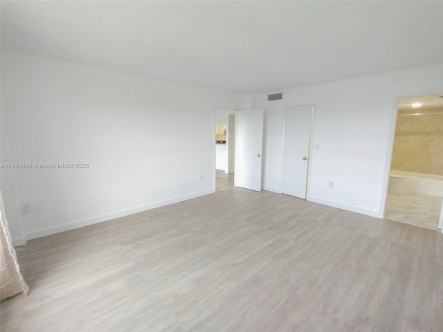 unfurnished bedroom with ensuite bath and light hardwood / wood-style flooring