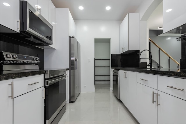 kitchen with sink, stainless steel appliances, dark stone counters, and white cabinets