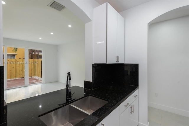 kitchen featuring white cabinetry, sink, and dark stone countertops