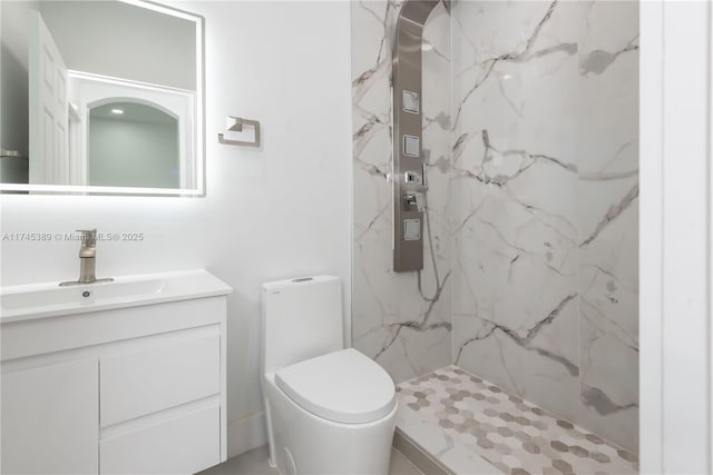 bathroom with vanity, toilet, and tiled shower