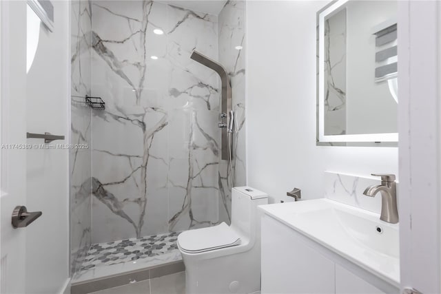 bathroom with vanity, tiled shower, and toilet