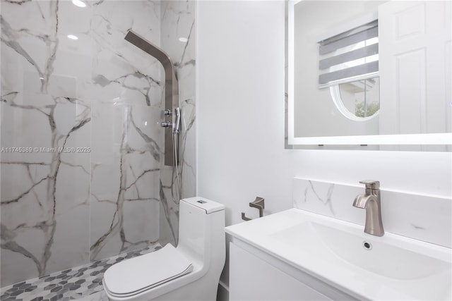 bathroom with vanity, tiled shower, and toilet