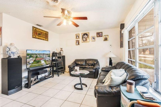 living room featuring light tile patterned flooring, ceiling fan, and a textured ceiling