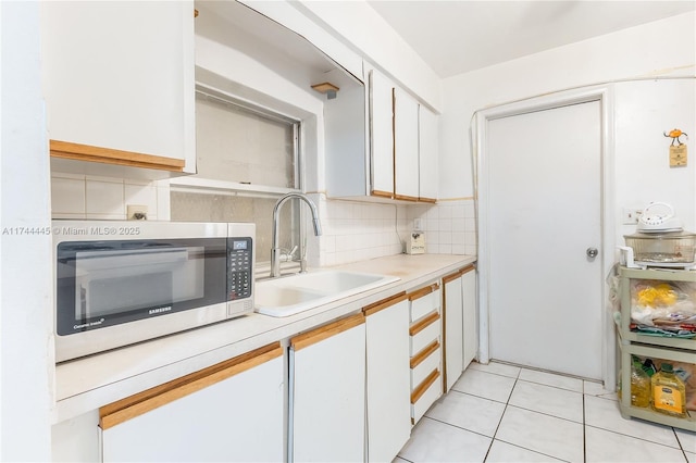 kitchen featuring white cabinetry, sink, decorative backsplash, and light tile patterned flooring