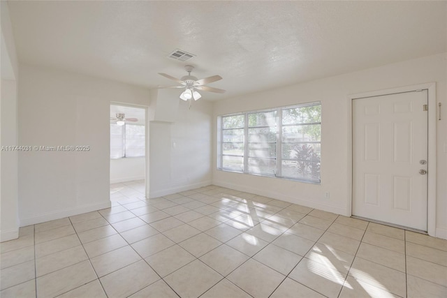 unfurnished room featuring ceiling fan, light tile patterned floors, and a textured ceiling