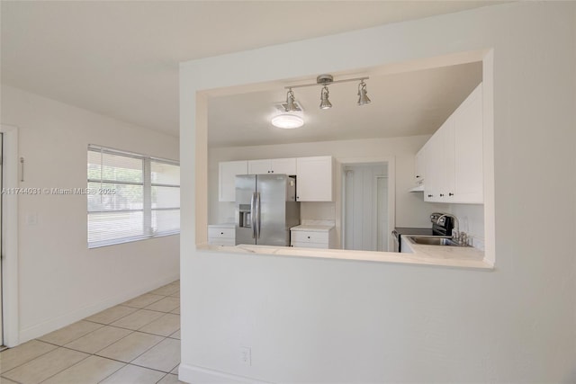 kitchen with sink, light tile patterned floors, appliances with stainless steel finishes, kitchen peninsula, and white cabinets