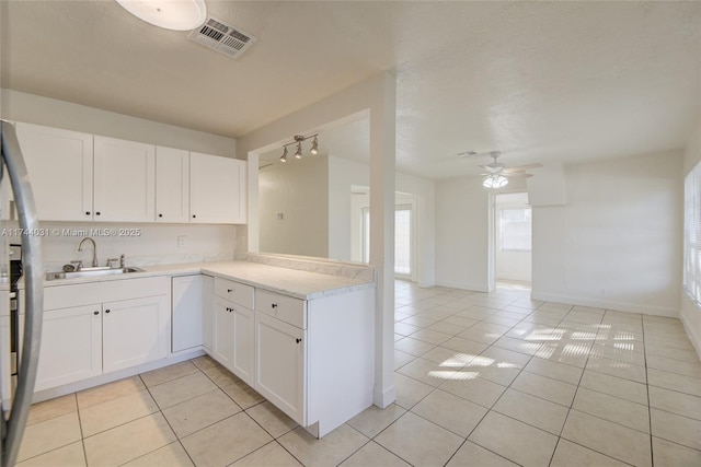 kitchen featuring light tile patterned floors, kitchen peninsula, sink, and white cabinets