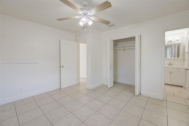 unfurnished bedroom with ensuite bathroom, sink, light tile patterned floors, ceiling fan, and a closet