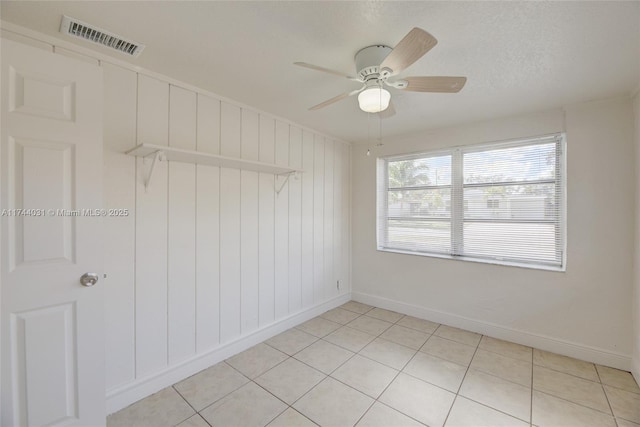 empty room featuring light tile patterned flooring, ceiling fan, and a textured ceiling