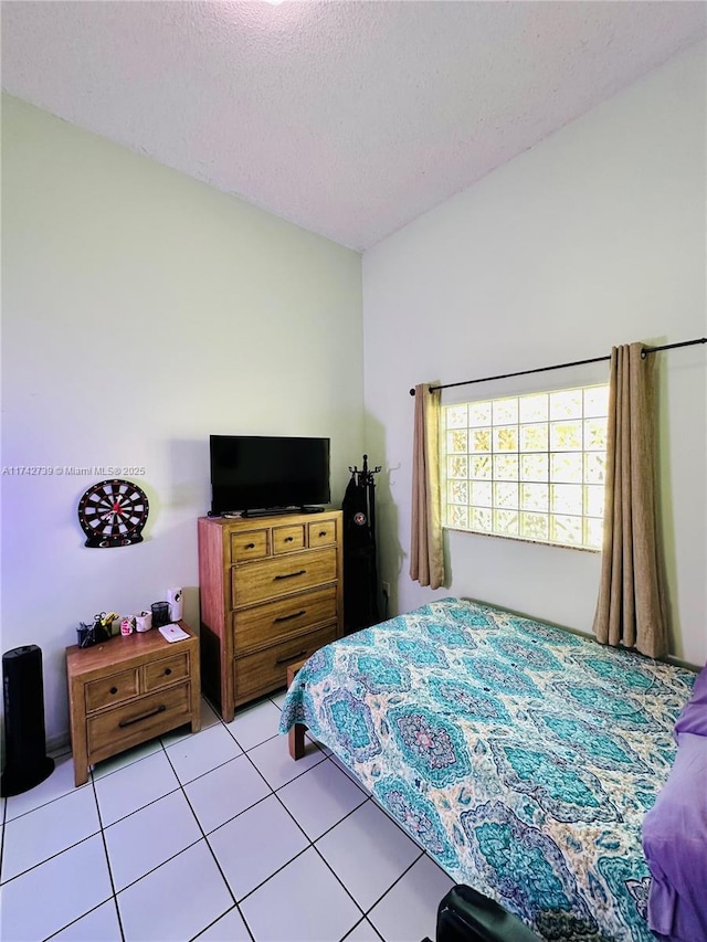 bedroom featuring a textured ceiling, lofted ceiling, and light tile patterned floors