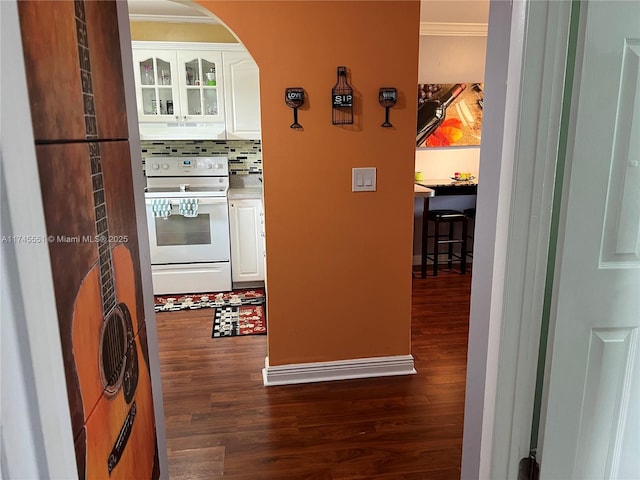 kitchen with electric stove, backsplash, white cabinetry, and crown molding