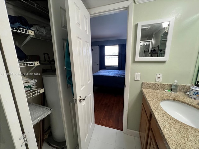 bathroom with water heater, vanity, ornamental molding, and tile patterned flooring