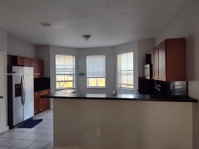 kitchen with light tile patterned floors, a wealth of natural light, stainless steel appliances, and kitchen peninsula