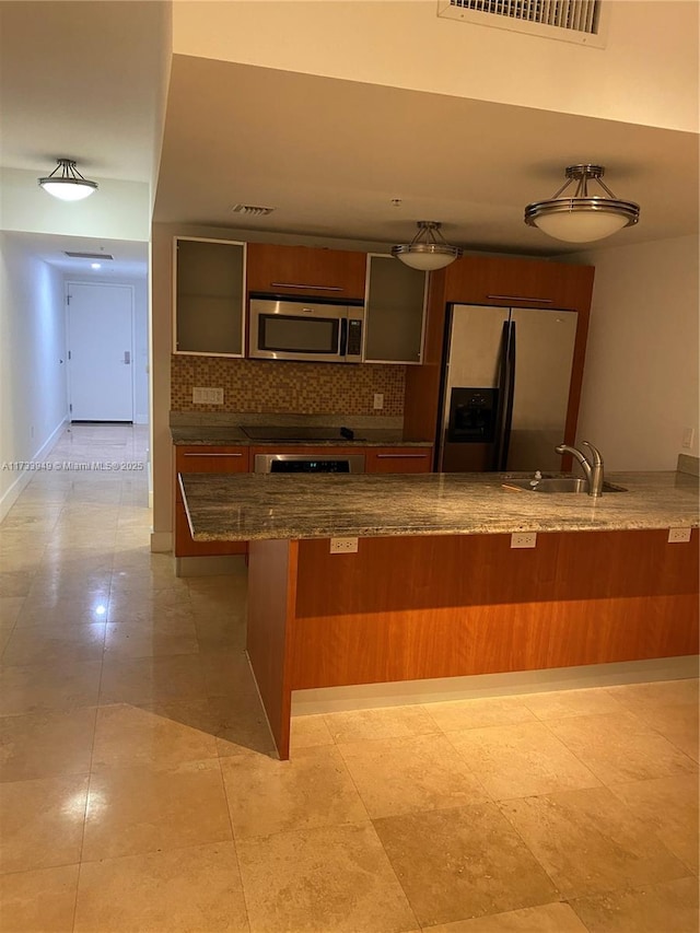 kitchen with sink, appliances with stainless steel finishes, a kitchen breakfast bar, kitchen peninsula, and decorative backsplash