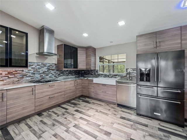 kitchen with tasteful backsplash, appliances with stainless steel finishes, sink, and wall chimney exhaust hood