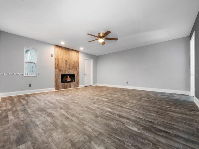 unfurnished living room featuring a tiled fireplace, dark hardwood / wood-style floors, and ceiling fan