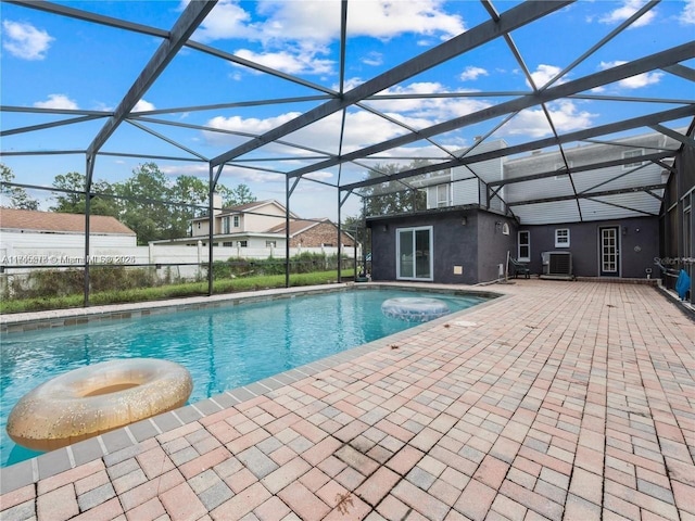 view of swimming pool featuring a patio, central AC unit, and glass enclosure