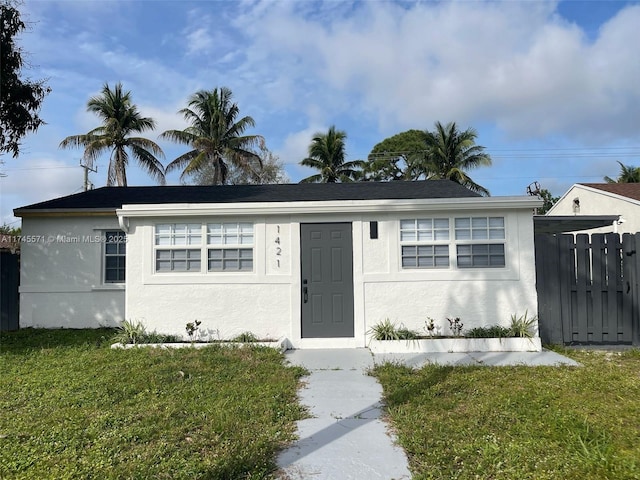 view of front of property with a front yard, fence, and stucco siding