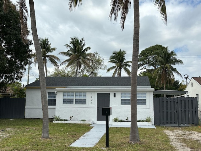 view of front of property featuring roof with shingles, fence, a front lawn, and stucco siding