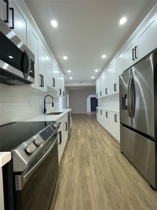 kitchen with light countertops, appliances with stainless steel finishes, a sink, and white cabinets