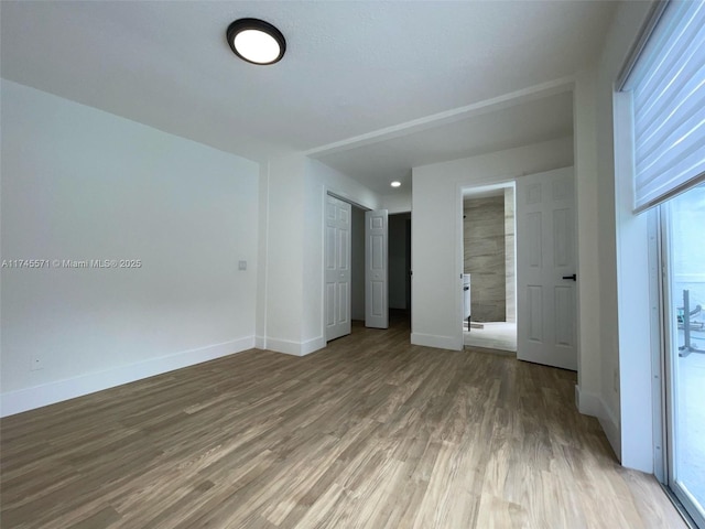 unfurnished bedroom featuring a closet, baseboards, and wood finished floors