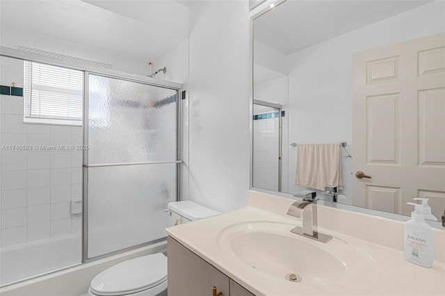 full bathroom with vanity, shower / bath combination with glass door, and toilet