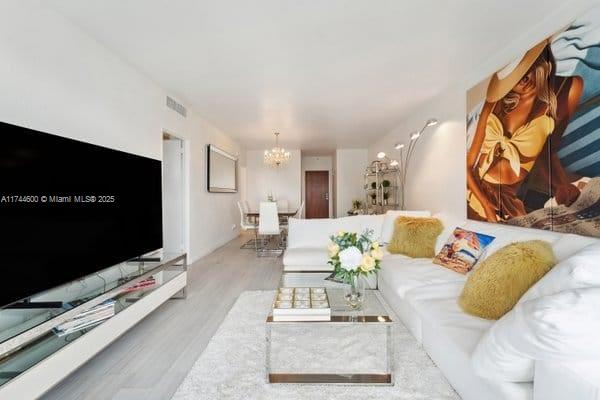 living room featuring an inviting chandelier and light wood-type flooring