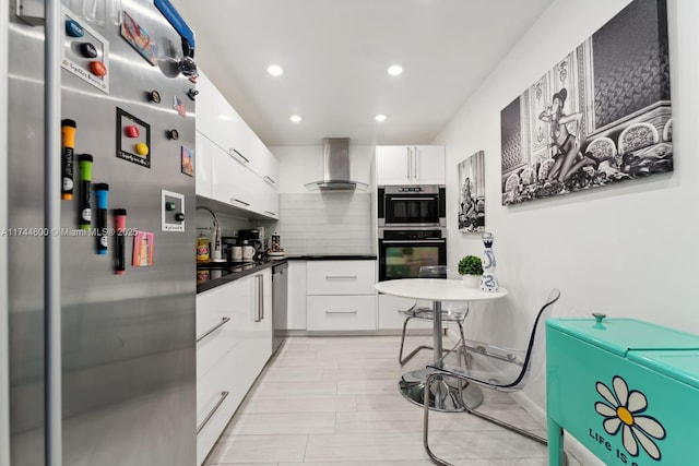 kitchen featuring tasteful backsplash, white cabinetry, appliances with stainless steel finishes, and wall chimney range hood