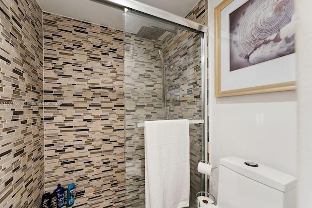 bathroom featuring toilet and a shower with shower door